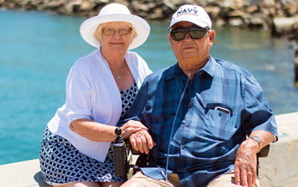 Elderly man in wheelchair using oxygen, next to his wife