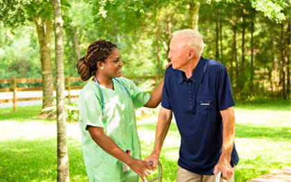 Caregiver helping elderly man with walker