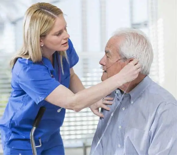 Caregiver assisting elderly man with oxygen